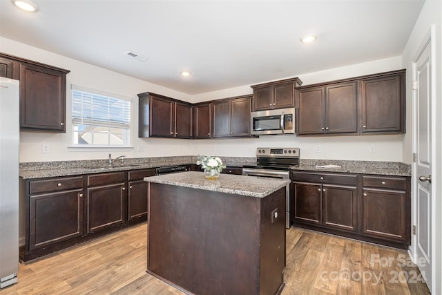 kitchen with light hardwood / wood-style flooring, a center island, dark brown cabinets, and appliances with stainless steel finishes