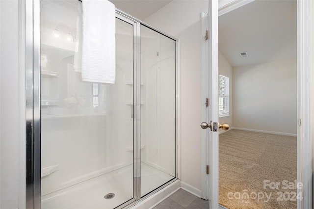 bathroom featuring walk in shower and lofted ceiling