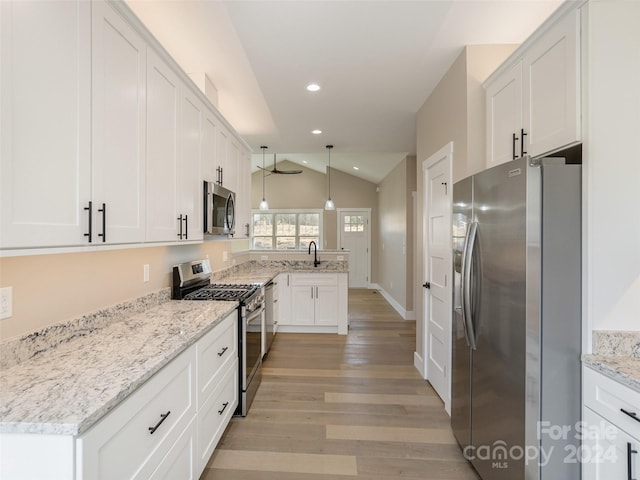 kitchen with stainless steel appliances, decorative light fixtures, light hardwood / wood-style floors, white cabinets, and lofted ceiling