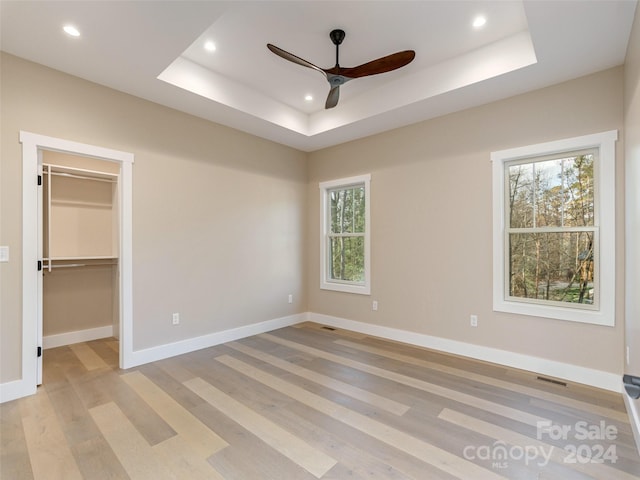 unfurnished bedroom with multiple windows, ceiling fan, a walk in closet, and a closet