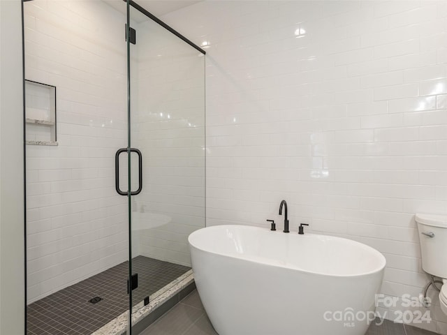 bathroom featuring toilet, shower with separate bathtub, tile walls, and tile patterned floors