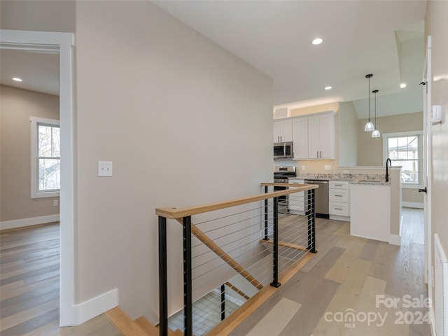 kitchen featuring a healthy amount of sunlight, white cabinetry, appliances with stainless steel finishes, and decorative light fixtures