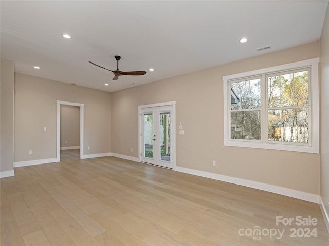 empty room featuring ceiling fan, a healthy amount of sunlight, light hardwood / wood-style flooring, and french doors