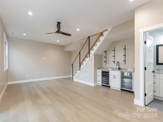 bar with beverage cooler, white cabinetry, and light hardwood / wood-style flooring