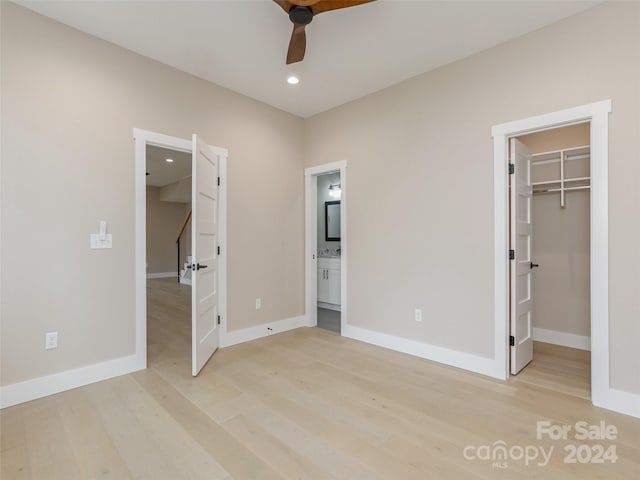 unfurnished bedroom featuring ensuite bathroom, a closet, light wood-type flooring, and a spacious closet