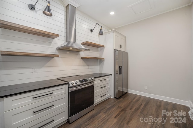 kitchen featuring dark wood-type flooring, ornamental molding, wall chimney range hood, white cabinetry, and appliances with stainless steel finishes