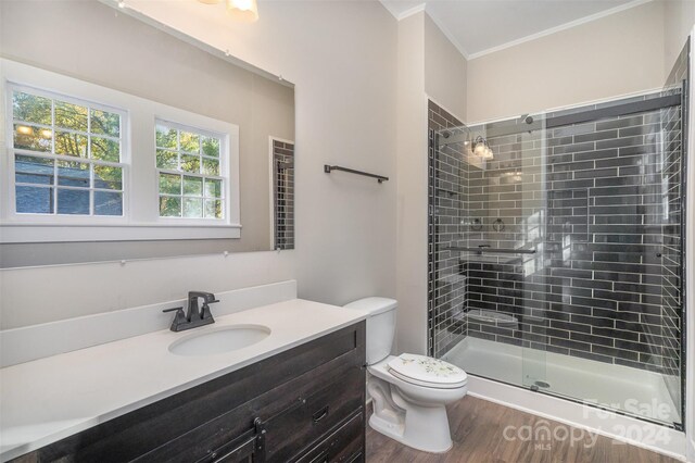 bathroom featuring hardwood / wood-style flooring, a tile shower, vanity, crown molding, and toilet