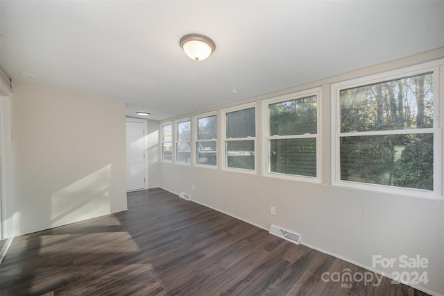 spare room with dark wood-type flooring and a wealth of natural light