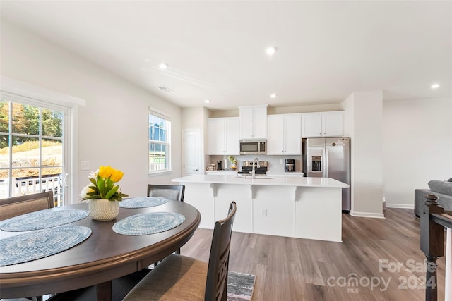 kitchen featuring an island with sink, a wealth of natural light, light hardwood / wood-style floors, and appliances with stainless steel finishes