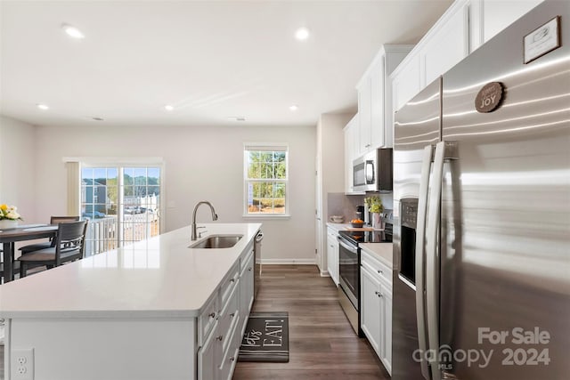 kitchen with white cabinetry, appliances with stainless steel finishes, sink, an island with sink, and dark wood-type flooring