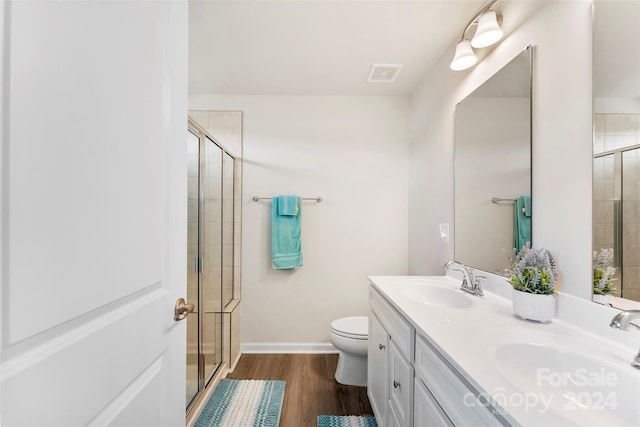 bathroom with wood-type flooring, vanity, toilet, and a shower with shower door