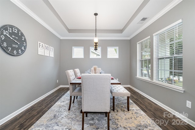 dining area with dark hardwood / wood-style floors and a tray ceiling