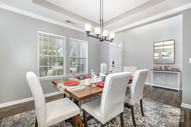 dining space with dark hardwood / wood-style flooring, crown molding, a tray ceiling, and a notable chandelier