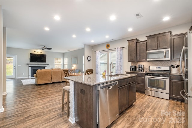 kitchen featuring stainless steel appliances, a center island with sink, sink, and light hardwood / wood-style floors