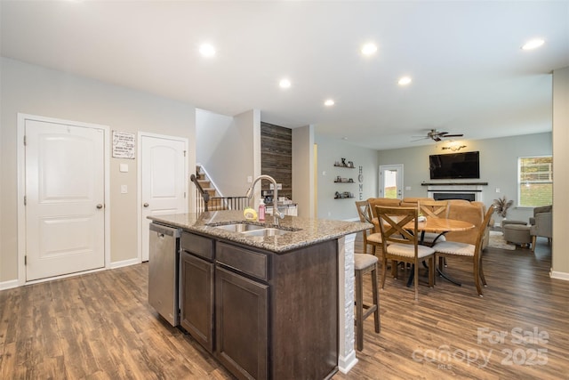 kitchen featuring a center island with sink, ceiling fan, sink, dark brown cabinets, and stainless steel dishwasher