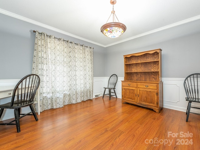 sitting room with ornamental molding and light wood-type flooring