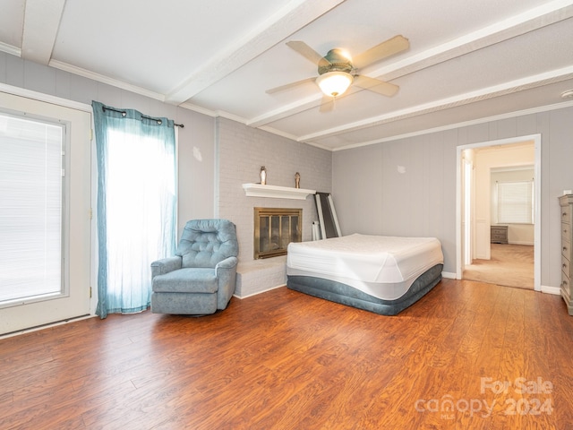 bedroom featuring beam ceiling, ceiling fan, hardwood / wood-style floors, and a brick fireplace