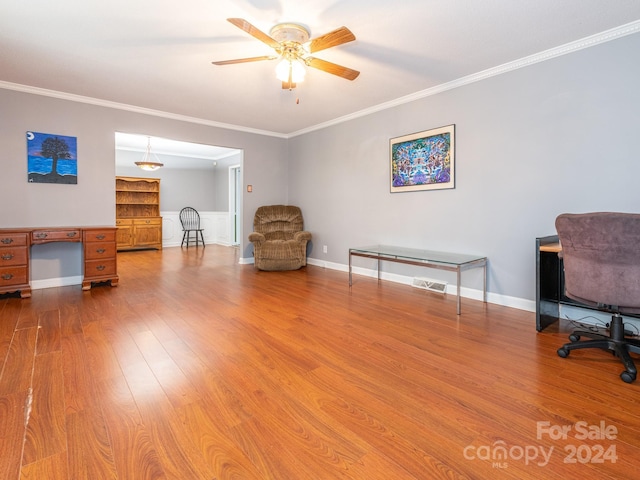 sitting room featuring wood-type flooring, ceiling fan, and crown molding