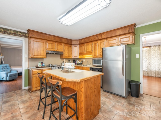 kitchen with a breakfast bar, light hardwood / wood-style flooring, ornamental molding, a kitchen island, and stainless steel appliances