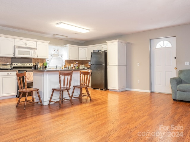 kitchen featuring a breakfast bar, refrigerator, white cabinetry, and backsplash