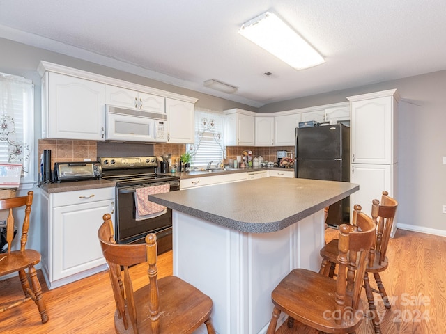 kitchen with black appliances, white cabinets, sink, light hardwood / wood-style flooring, and tasteful backsplash