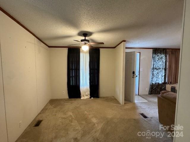 carpeted spare room with ceiling fan, a textured ceiling, and ornamental molding