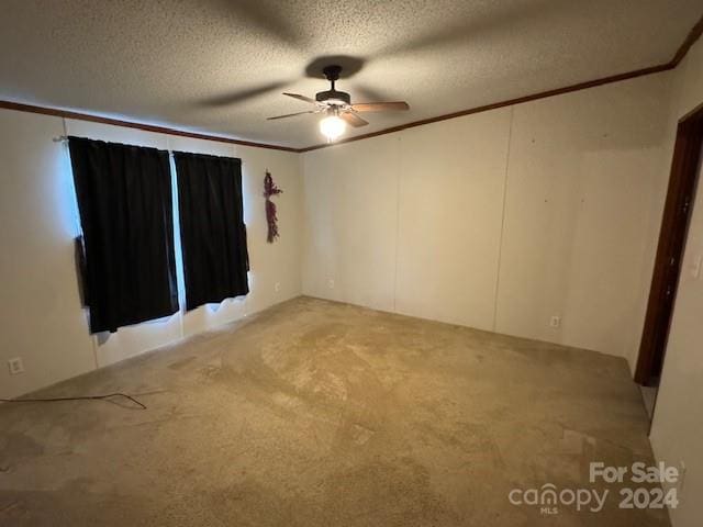 carpeted empty room featuring a textured ceiling, ceiling fan, and crown molding