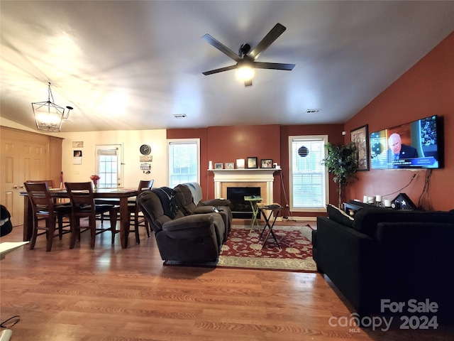 living room with lofted ceiling, hardwood / wood-style flooring, and ceiling fan with notable chandelier