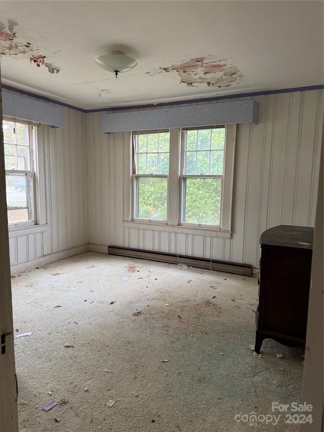 unfurnished room featuring carpet flooring and a baseboard heating unit