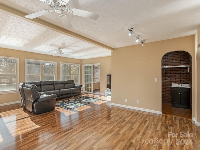 living room with hardwood / wood-style floors, a textured ceiling, ceiling fan, and beam ceiling