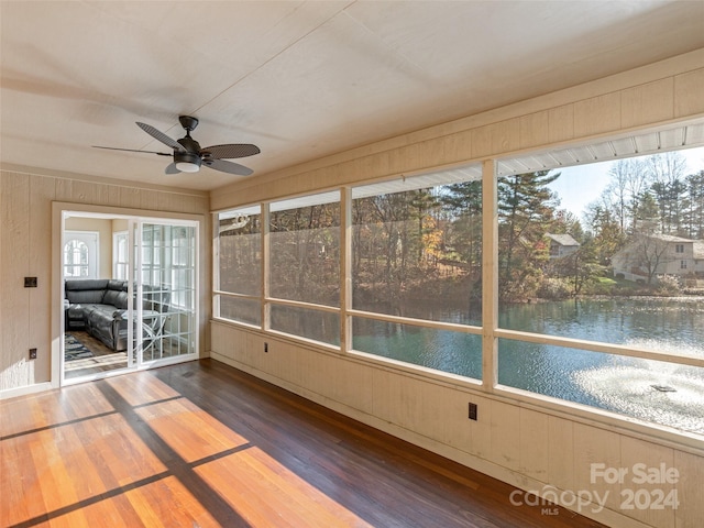 unfurnished sunroom with ceiling fan and a water view