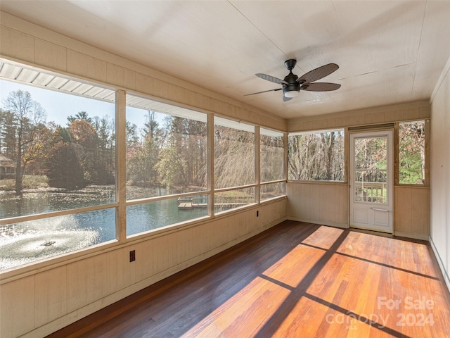 unfurnished sunroom featuring ceiling fan and a water view