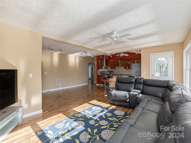 living room with a textured ceiling, hardwood / wood-style flooring, and ceiling fan