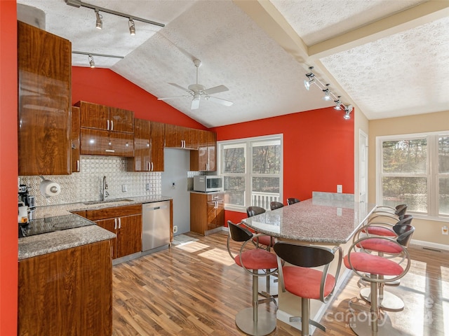 kitchen featuring stainless steel appliances, sink, vaulted ceiling, and light hardwood / wood-style flooring