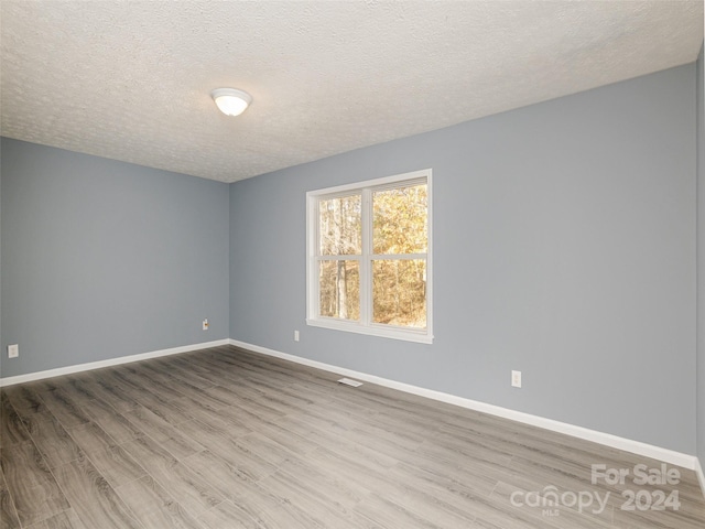 empty room with wood-type flooring and a textured ceiling