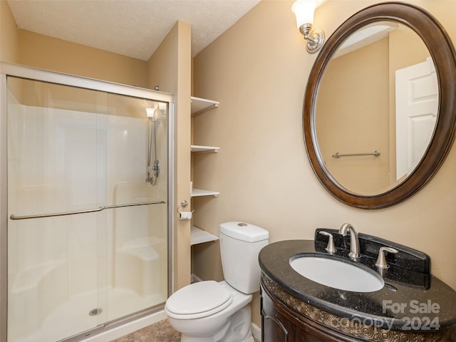 bathroom featuring vanity, walk in shower, a textured ceiling, and toilet