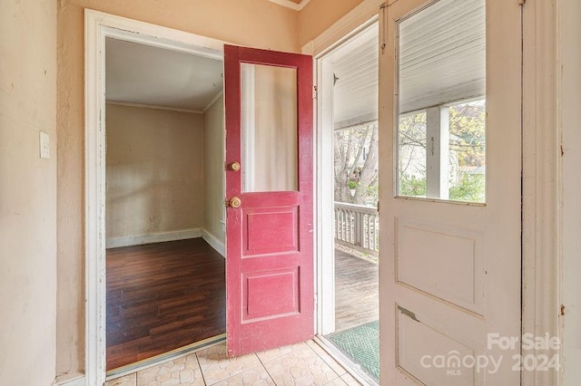 doorway featuring light wood-type flooring and crown molding