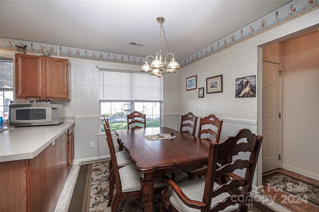 dining area with a chandelier, a healthy amount of sunlight, and a textured ceiling