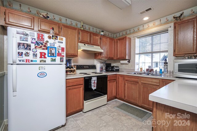 kitchen with white appliances, sink, and a textured ceiling