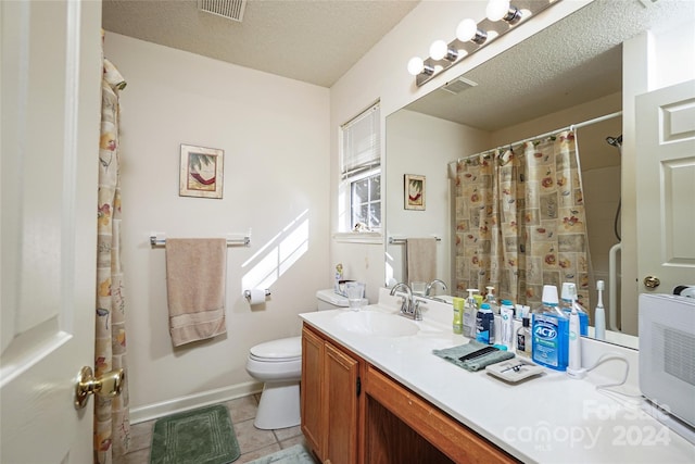 bathroom featuring toilet, vanity, a textured ceiling, and tile patterned floors