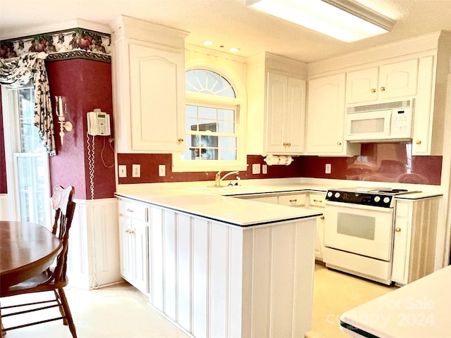 kitchen with kitchen peninsula, white appliances, white cabinetry, and sink