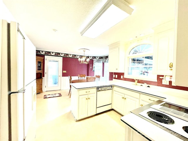 kitchen featuring sink, kitchen peninsula, a chandelier, decorative light fixtures, and white appliances