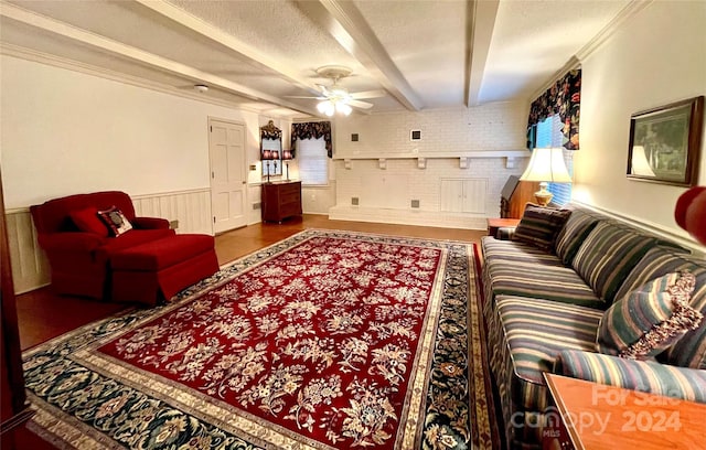 living room featuring beamed ceiling, ceiling fan, crown molding, and brick wall