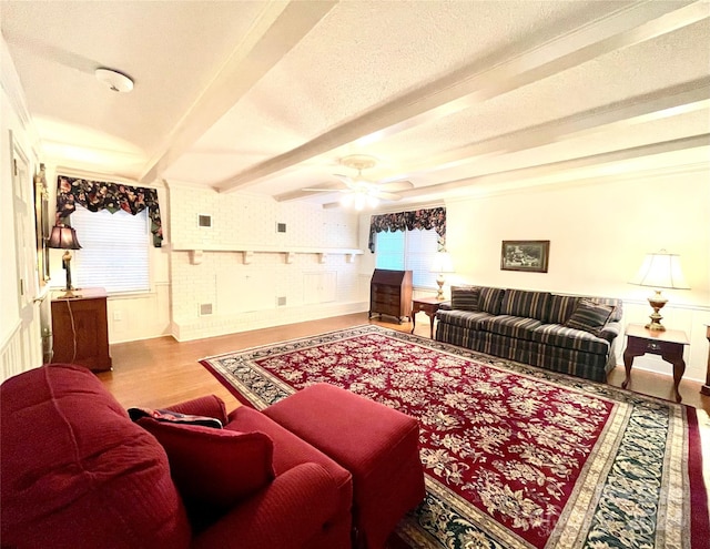 living room featuring beam ceiling, a textured ceiling, ceiling fan, and wood-type flooring