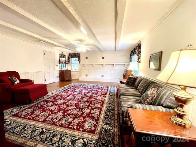 living room with beam ceiling, ceiling fan, brick wall, crown molding, and a textured ceiling