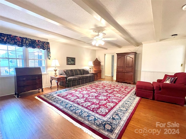 living room featuring beamed ceiling, wood-type flooring, a textured ceiling, and ceiling fan