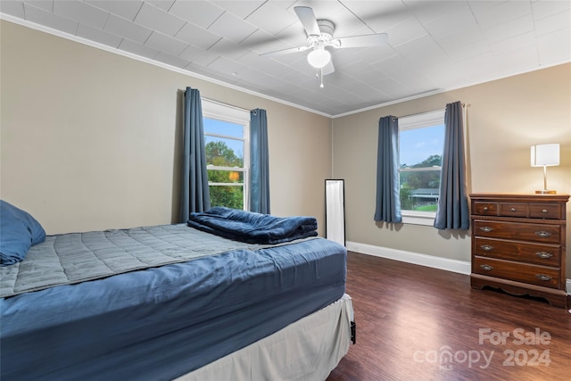 bedroom featuring ceiling fan, ornamental molding, and dark wood-type flooring