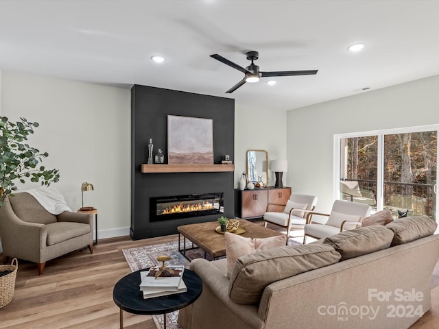 living room with ceiling fan, a fireplace, and light hardwood / wood-style flooring