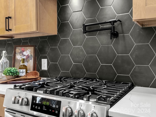 kitchen featuring backsplash and stainless steel gas range oven