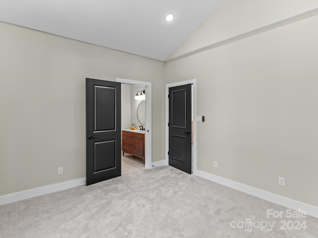 unfurnished bedroom featuring light colored carpet and lofted ceiling